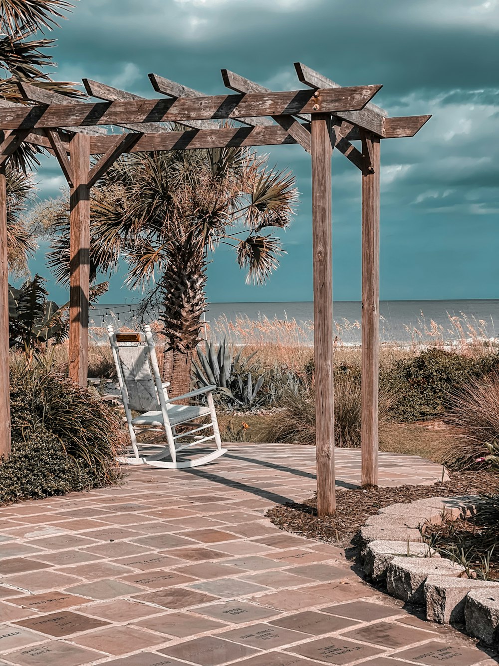 white wooden chair on brown concrete floor near body of water during daytime