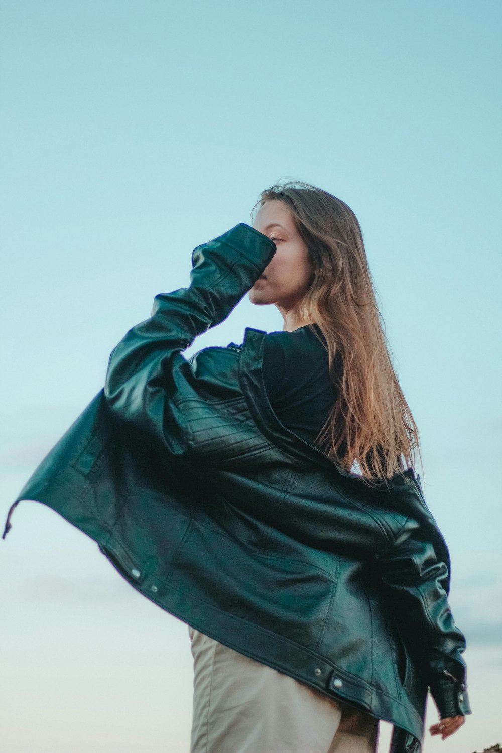 woman in black leather jacket covering her face with her hair