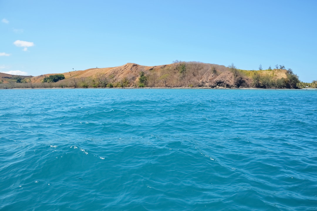 green and brown mountain beside body of water during daytime