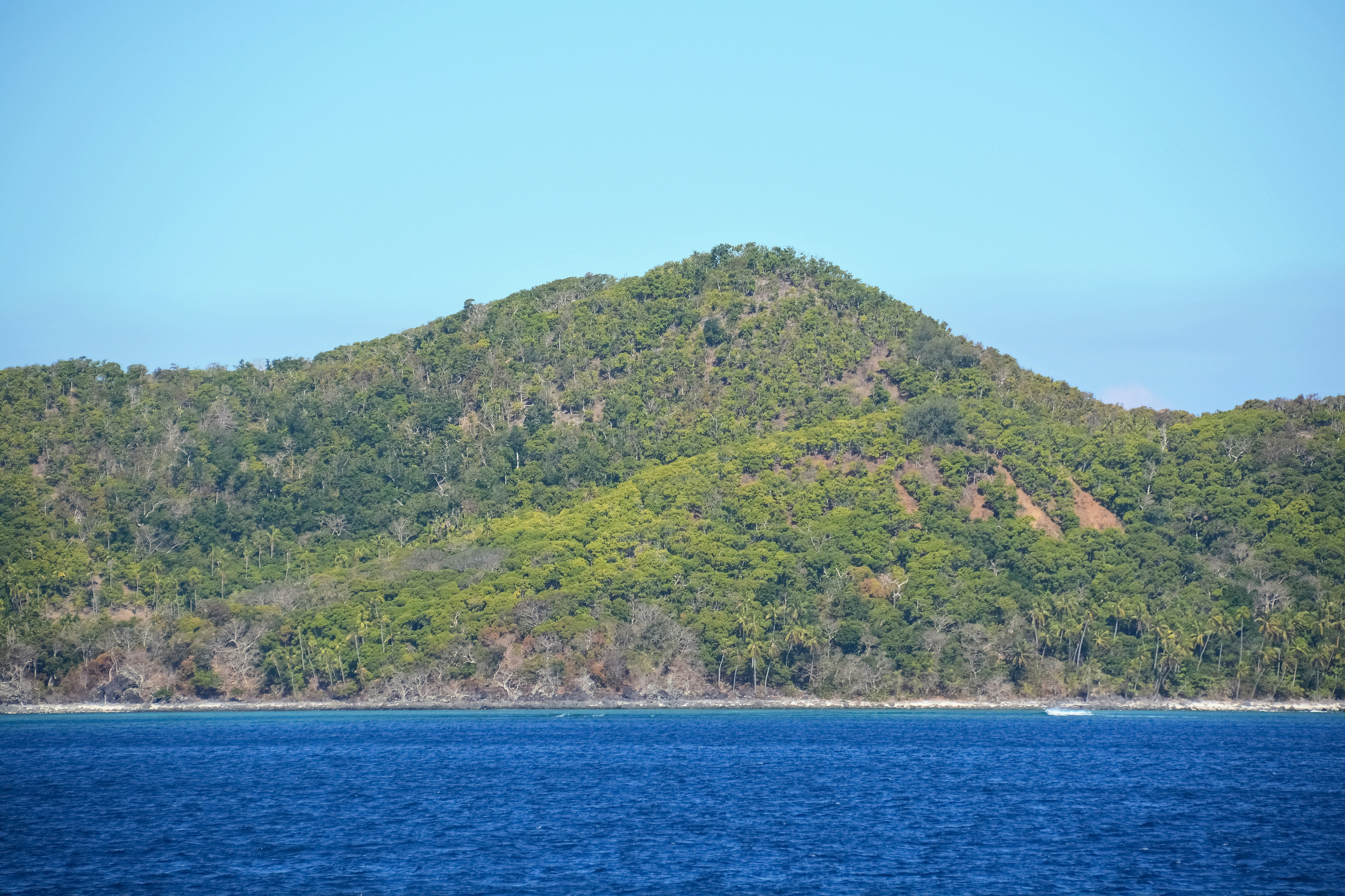 green mountain beside blue sea under blue sky during daytime