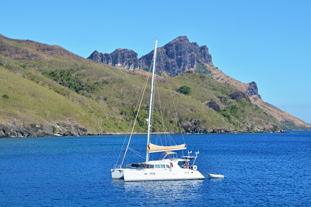 white boat on sea near mountain during daytime