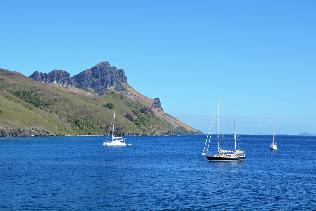 white boat on blue sea near mountain during daytime