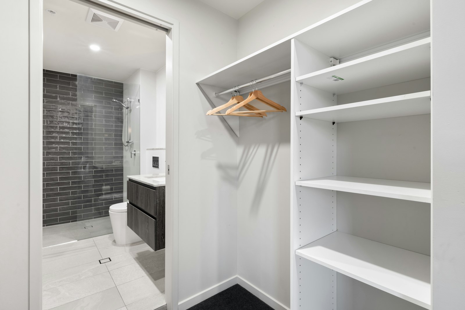 White wooden shelving and a mirror in a bright walk-in closet