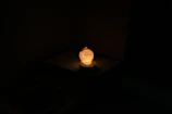 Soft glowing lamp shaped like a peach illuminating a bedside table.
