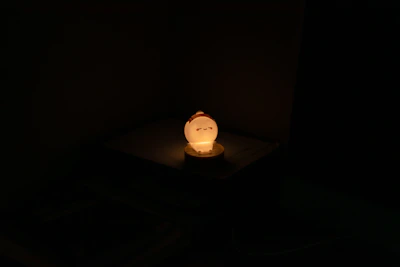 Soft glowing lamp shaped like a peach illuminating a bedside table.