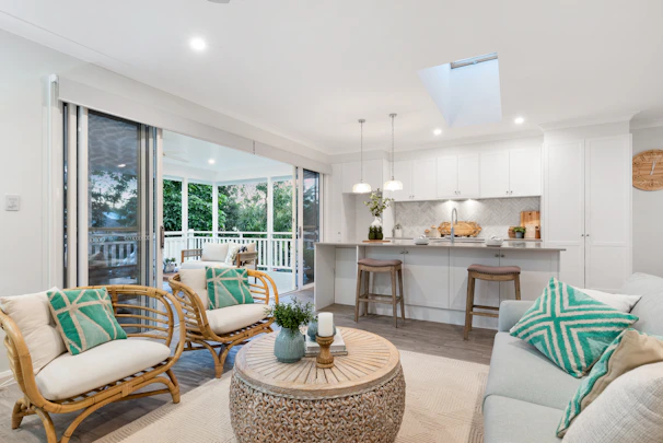 Open-plan living area blending indoor and outdoor spaces with rattan furniture and warm neutral tones.