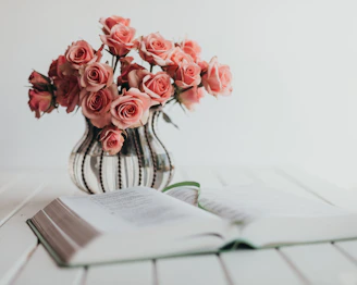 Soft pink roses next to a sleek appointment book on a light wood table.