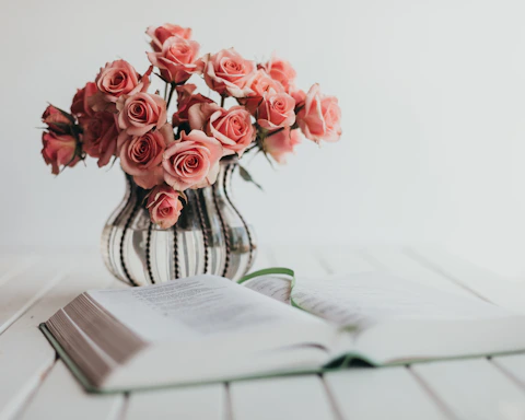 Soft pink roses next to a sleek appointment book on a light wood table.