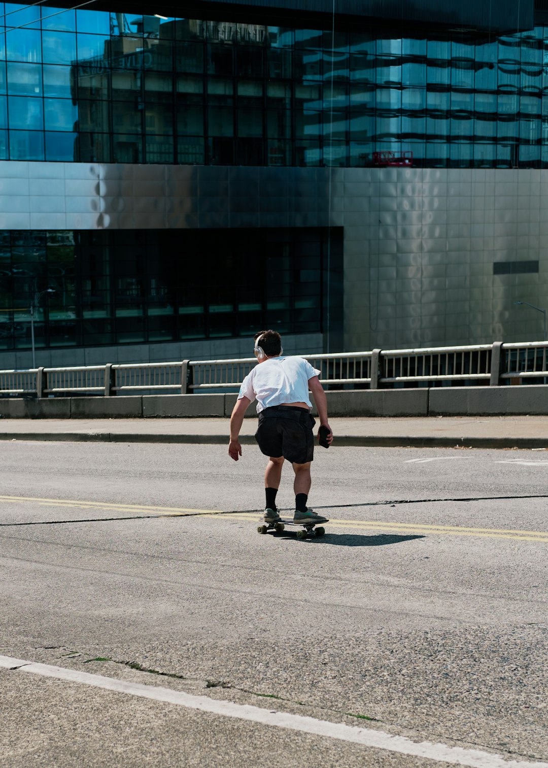 man in white t-shirt and black shorts running on road during daytime