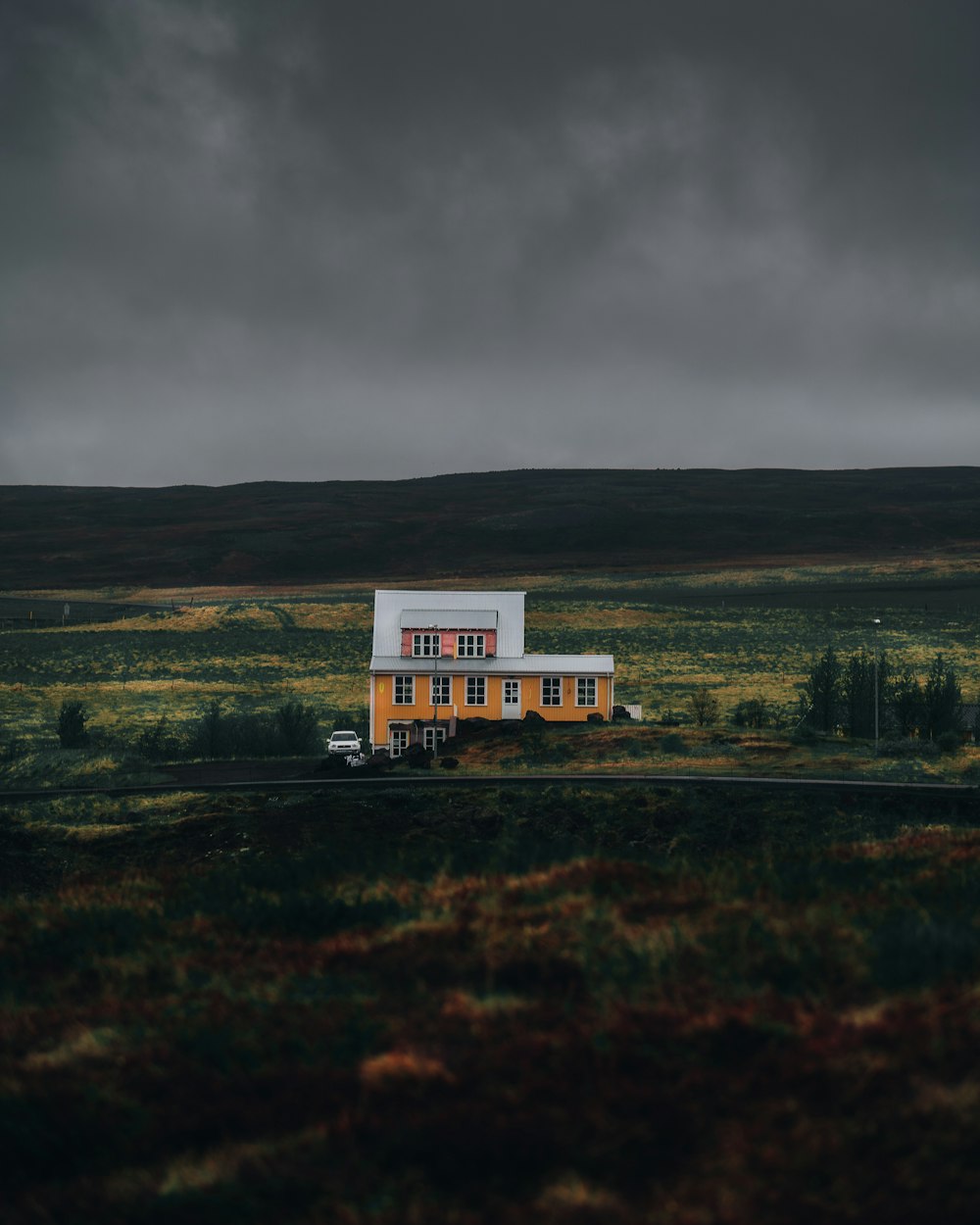 white and brown house on green grass field under gray sky