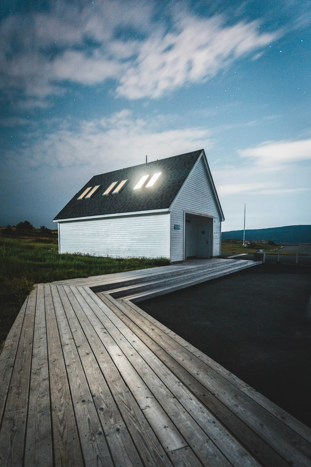 white and black wooden house near green grass field under blue sky during daytime