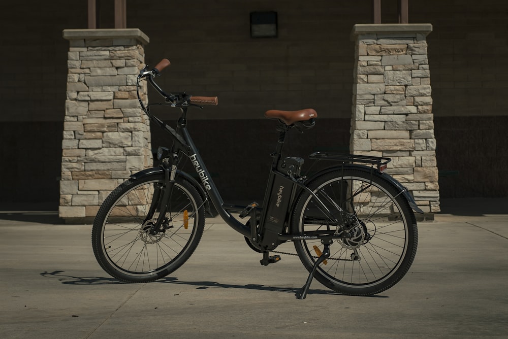 black commuter bike parked beside brown brick wall