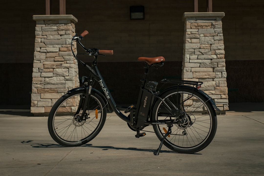 black commuter bike parked beside brown brick wall