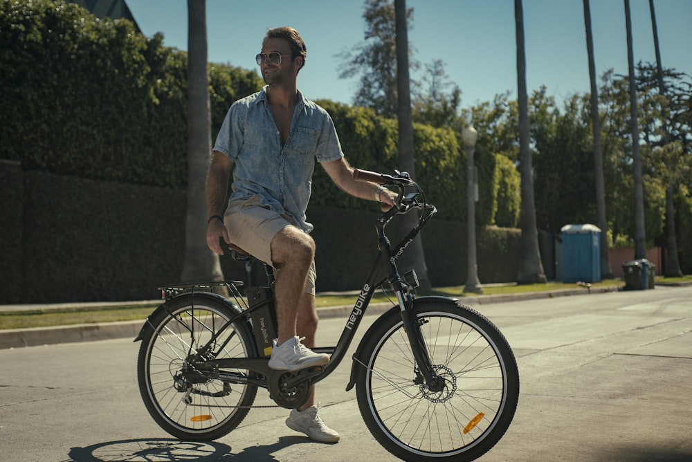 man in blue button up shirt riding on black bicycle during daytime