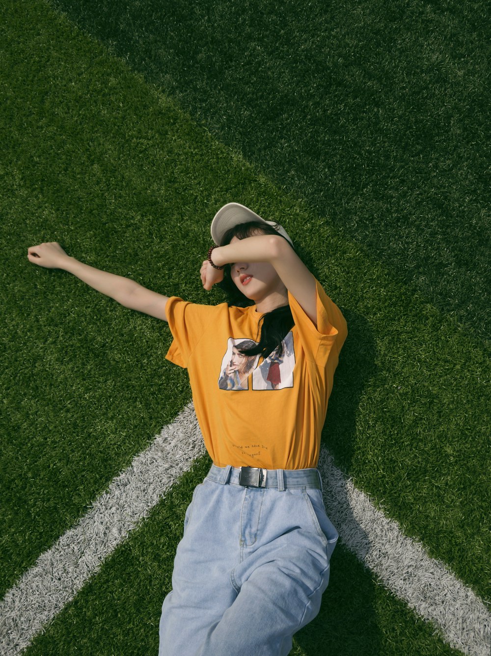 garçon en polo orange et noir couché sur un champ d’herbe verte pendant la journée
