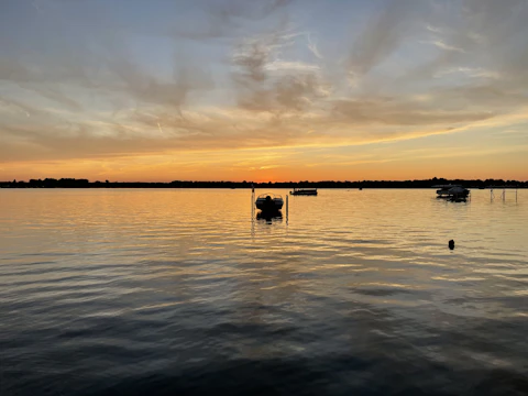 Sunset view over a calm lake with boats.