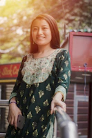 A vibrant dress with deep pockets holding a phone and keys, worn by a smiling woman outdoors.