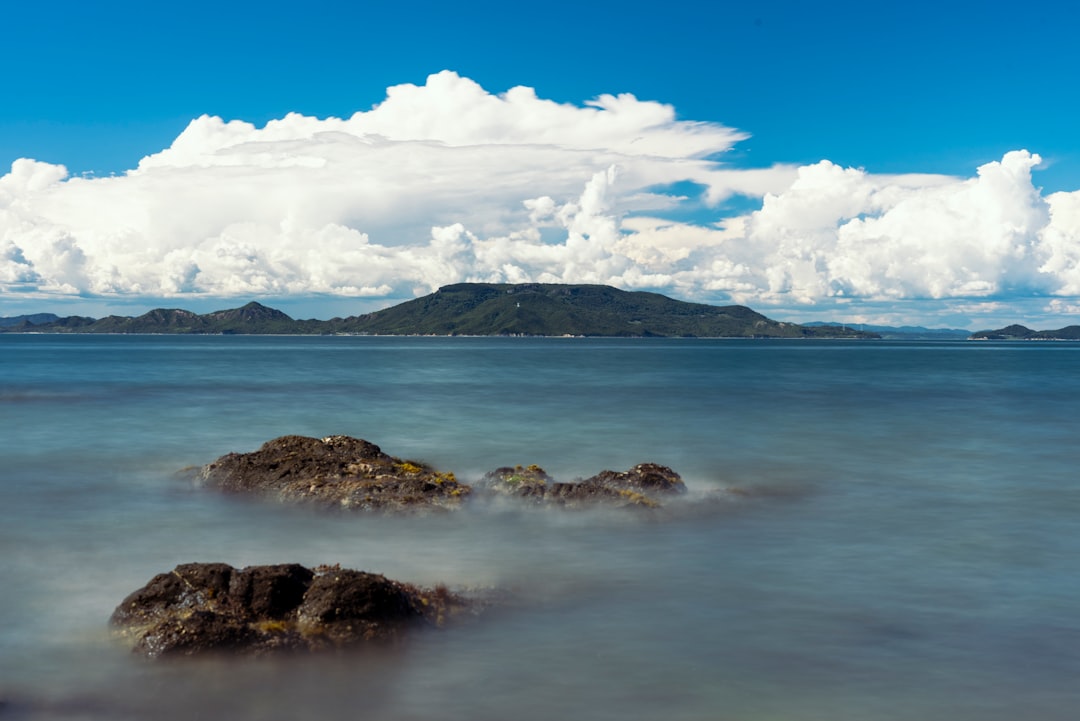 brown rocky mountain near body of water under blue sky during daytime