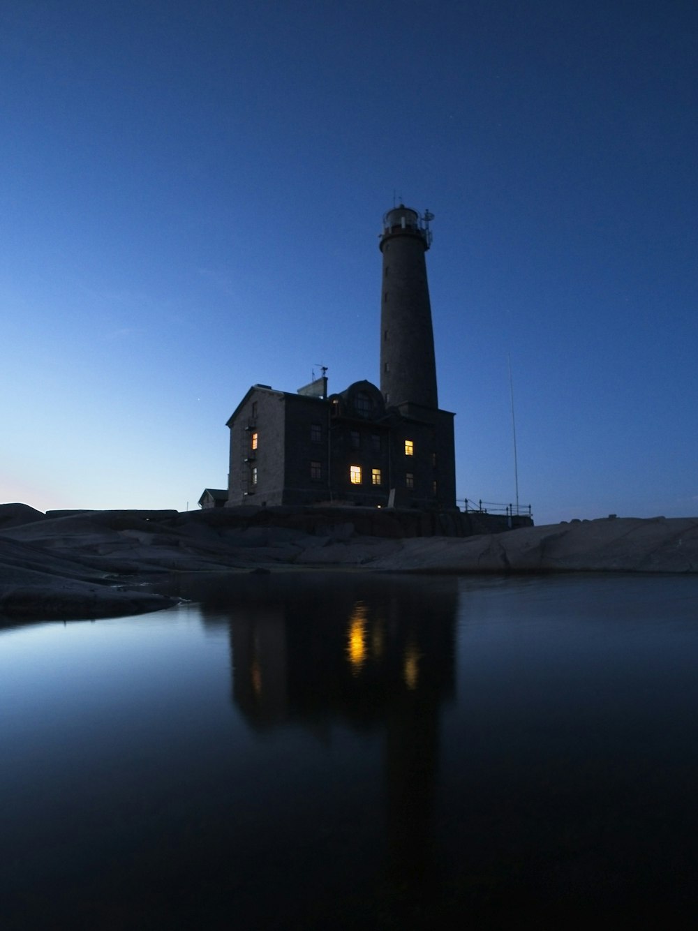 silhouette of lighthouse near body of water during night time