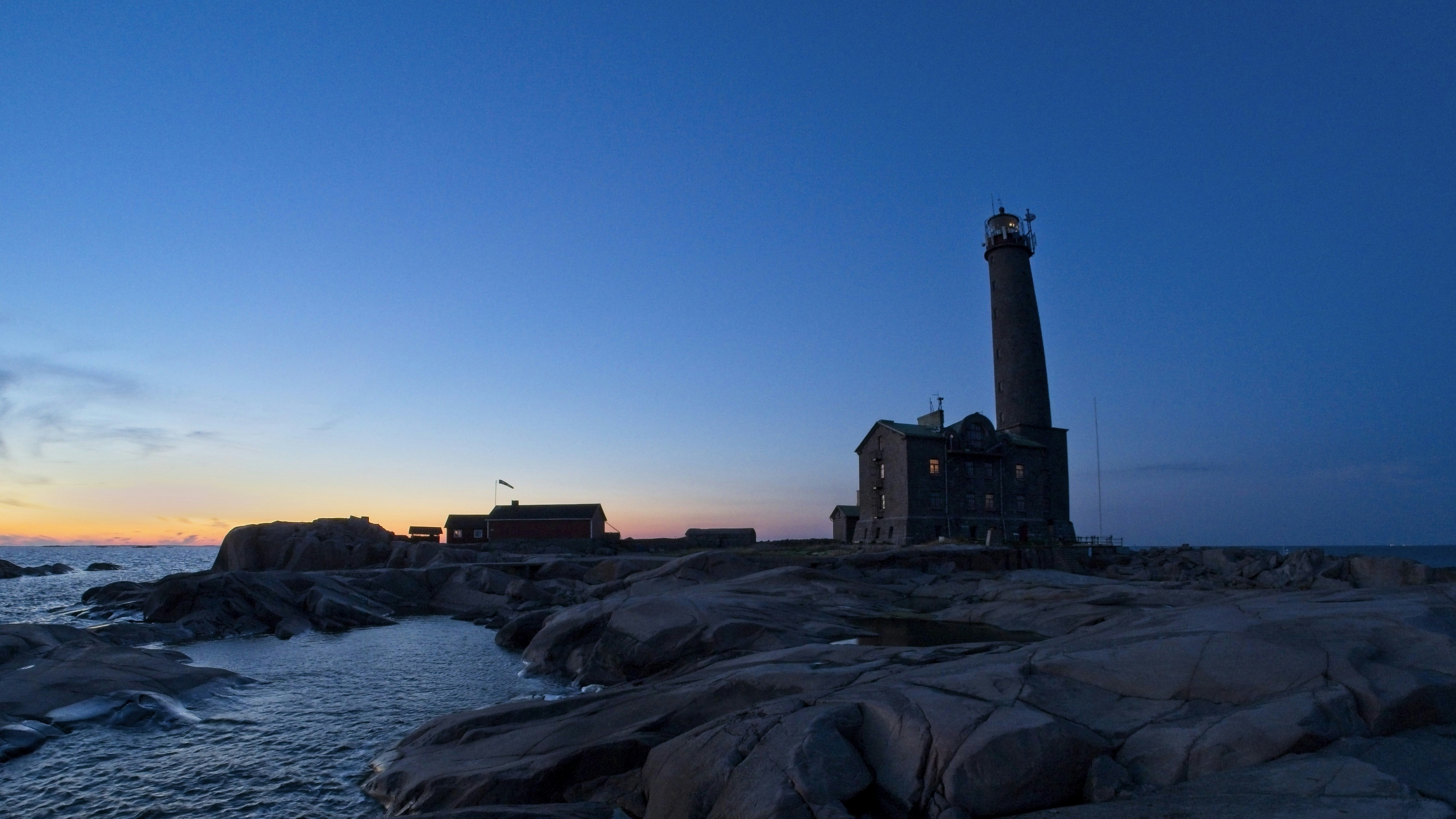 silhouette of lighthouse near body of water during sunset