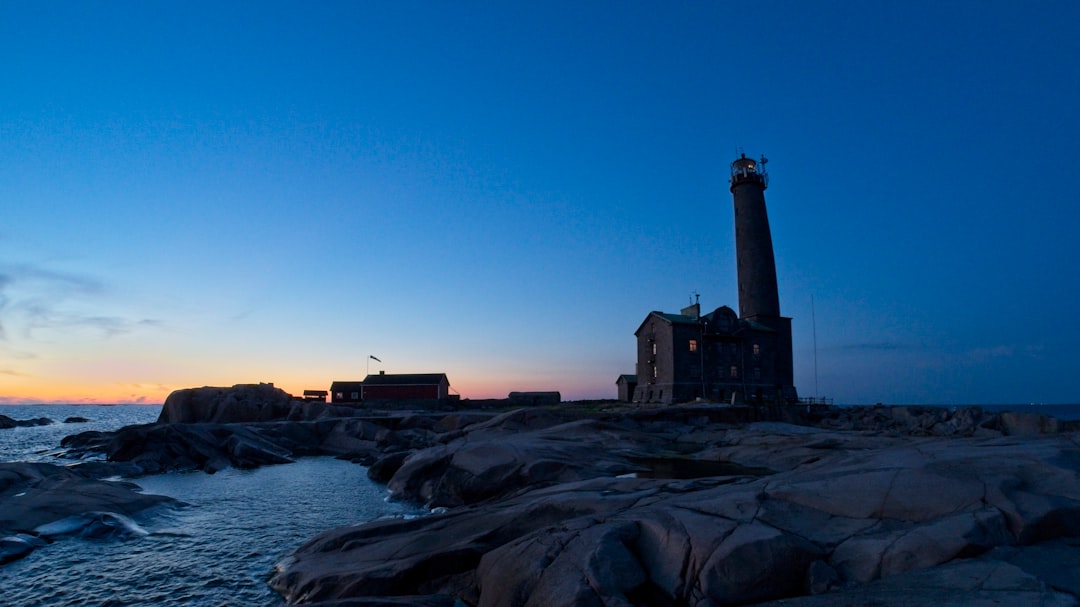 silhouette of lighthouse near body of water during sunset