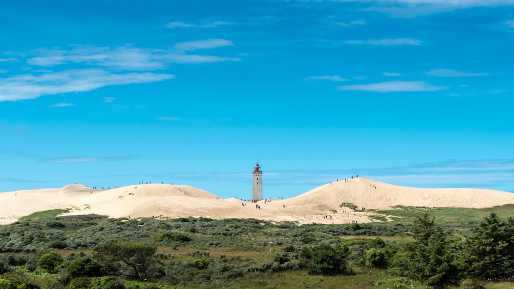 white lighthouse on brown sand under blue sky during daytime