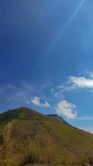 A lush green hillside with a clear blue sky, showcasing a spacious land plot ready for development.