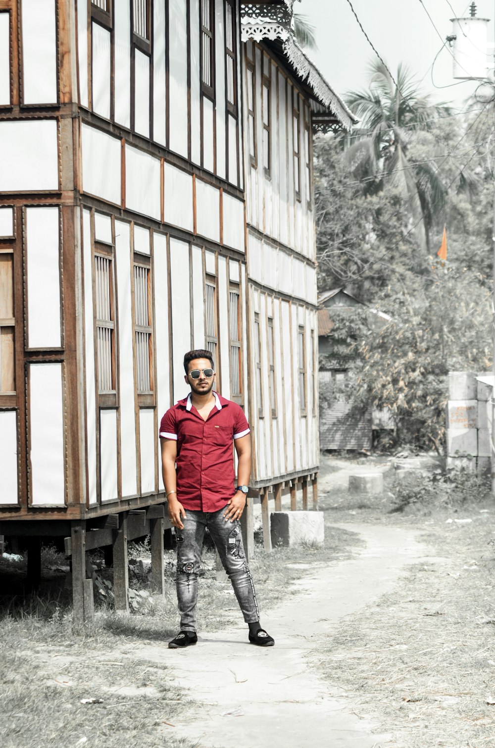 man in purple jacket standing beside brown wooden building during daytime