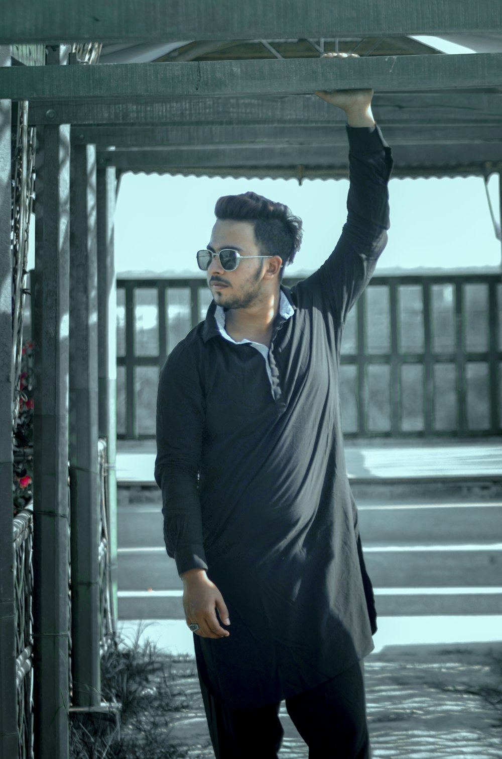 man in black long sleeve shirt and black pants wearing black sunglasses standing on gray concrete