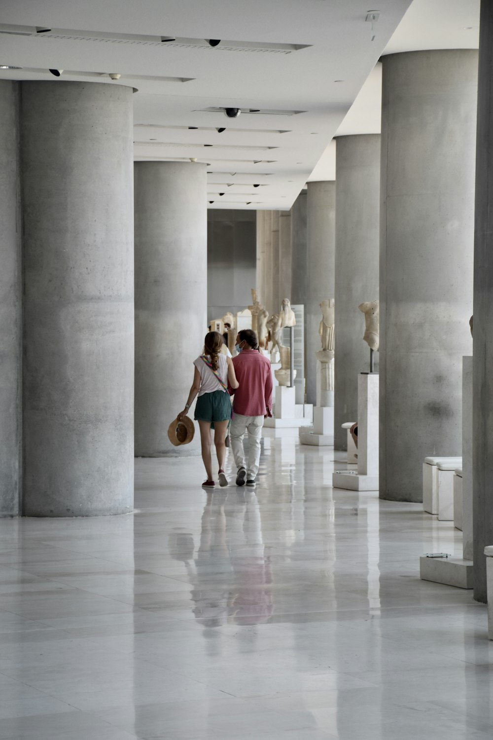 Hombre con camiseta azul y pantalones cortos blancos caminando por el pasillo