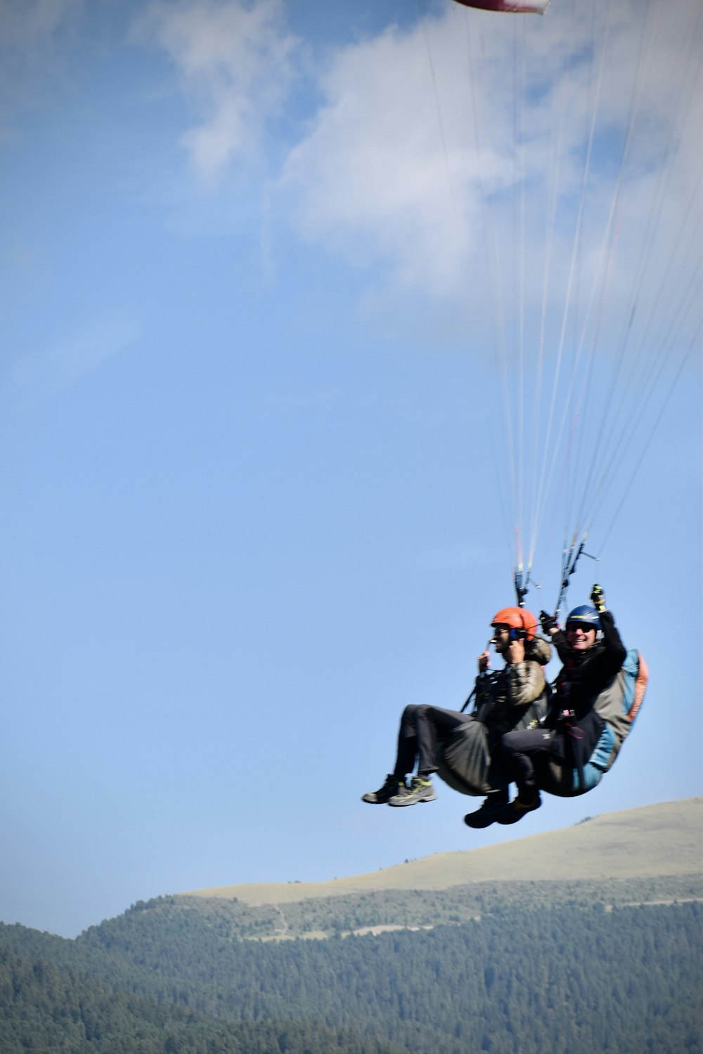 Homme en veste noire et casque orange chevauchant un parachute rouge et noir