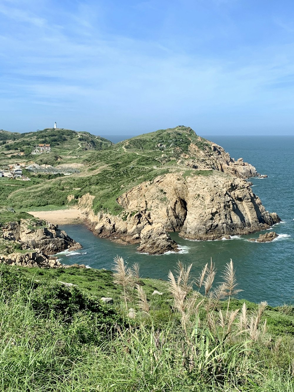 green and brown mountain beside blue sea under blue sky during daytime