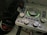 A close-up of an audio interface with various knobs, buttons, and indicators on its panel. The interface is accompanied by a pair of Sony dynamic stereo headphones, positioned to the left. The interface has LED lights illuminating in green around the central knob.