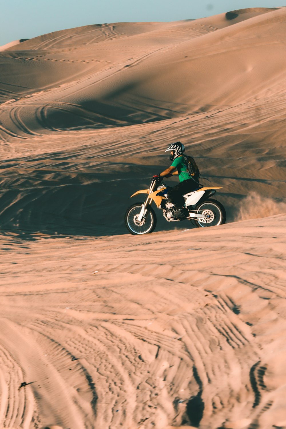 man riding motocross dirt bike on desert during daytime