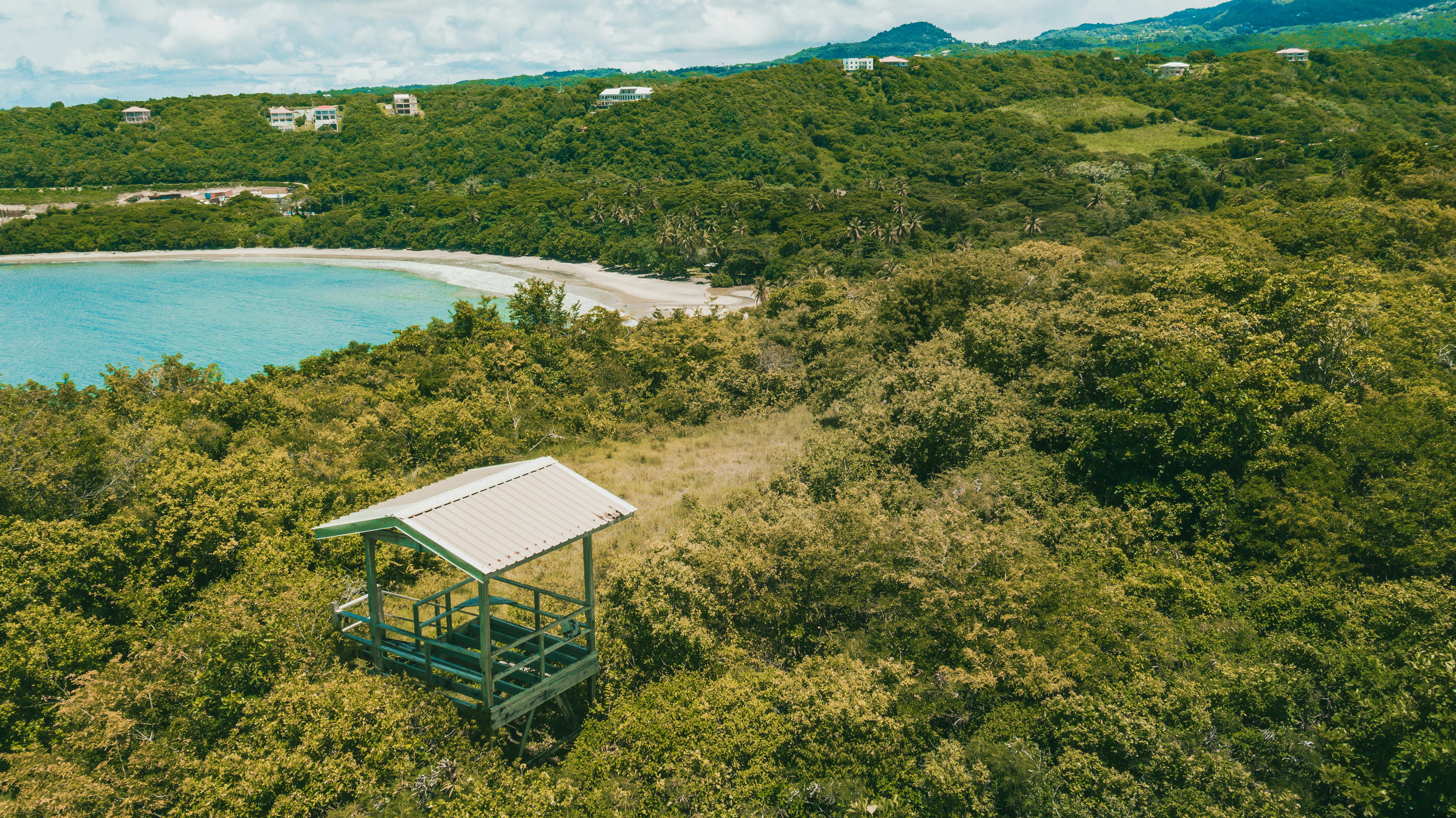 white and blue wooden house on green grass field near body of water during daytime