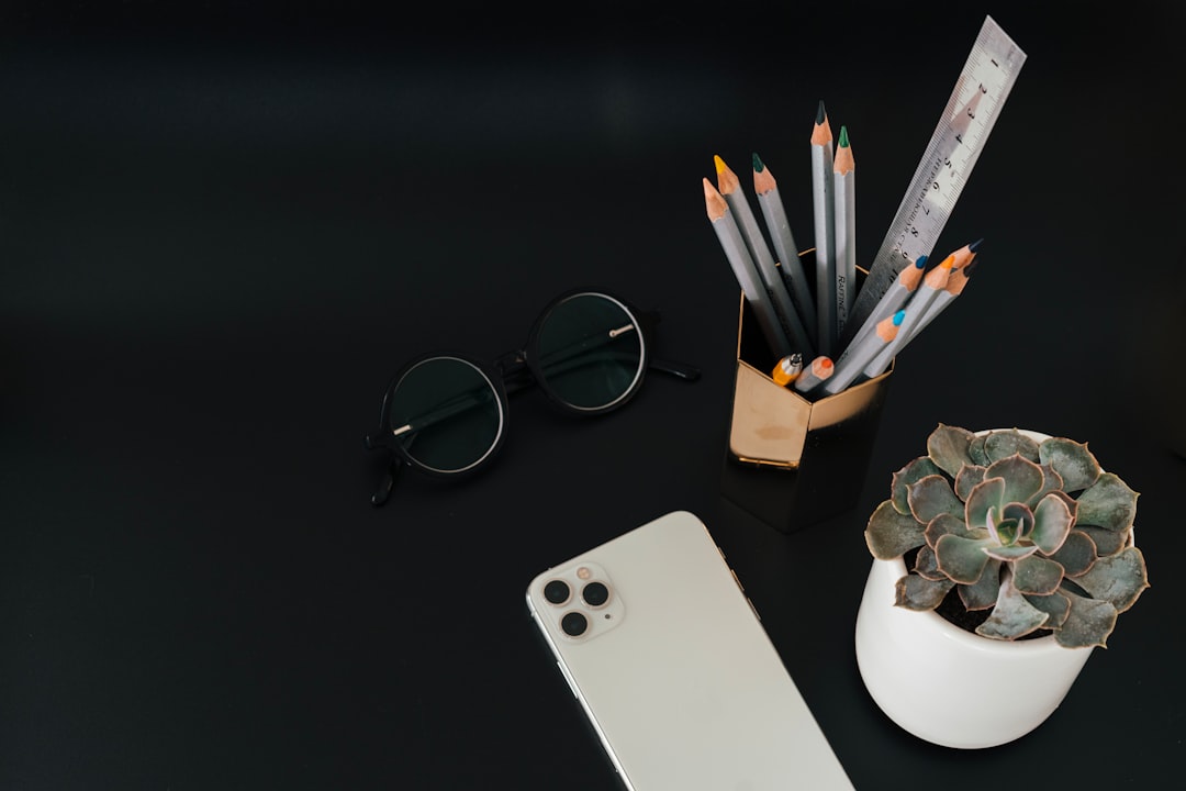 black framed eyeglasses beside silver iphone 6 and white ceramic mug on white table