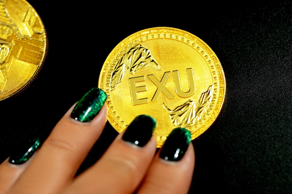 gold round coin on persons hand