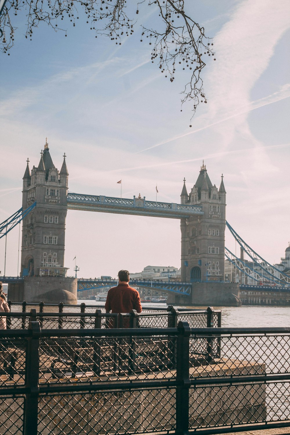 man in red jacket standing near bridge during daytime