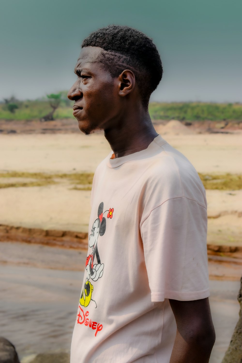 man in white crew neck t-shirt standing on brown field during daytime