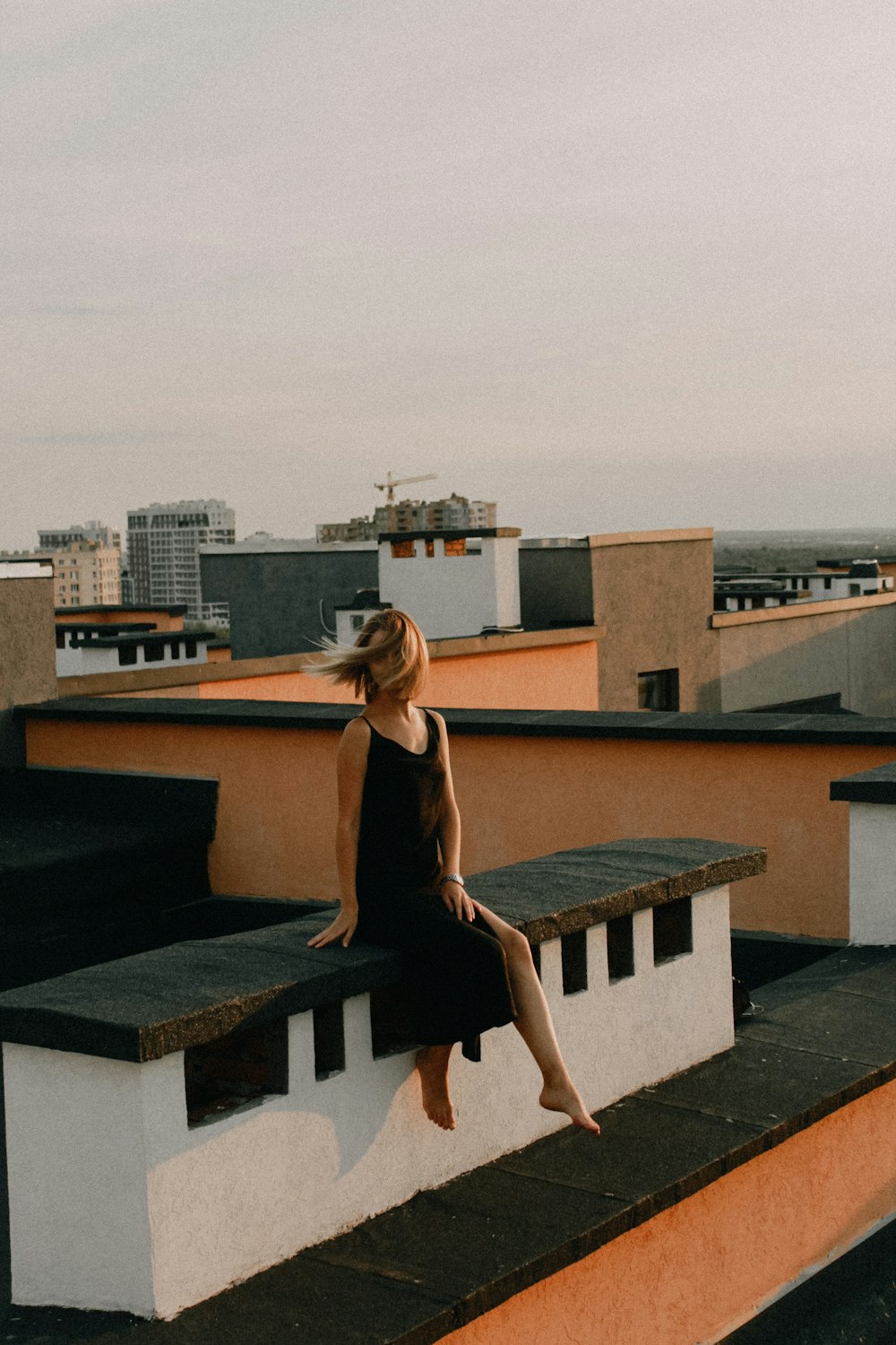 woman in black dress standing on roof top during daytime