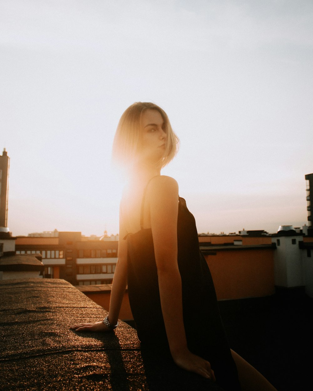 woman in black sleeveless dress sitting on brown concrete floor during daytime