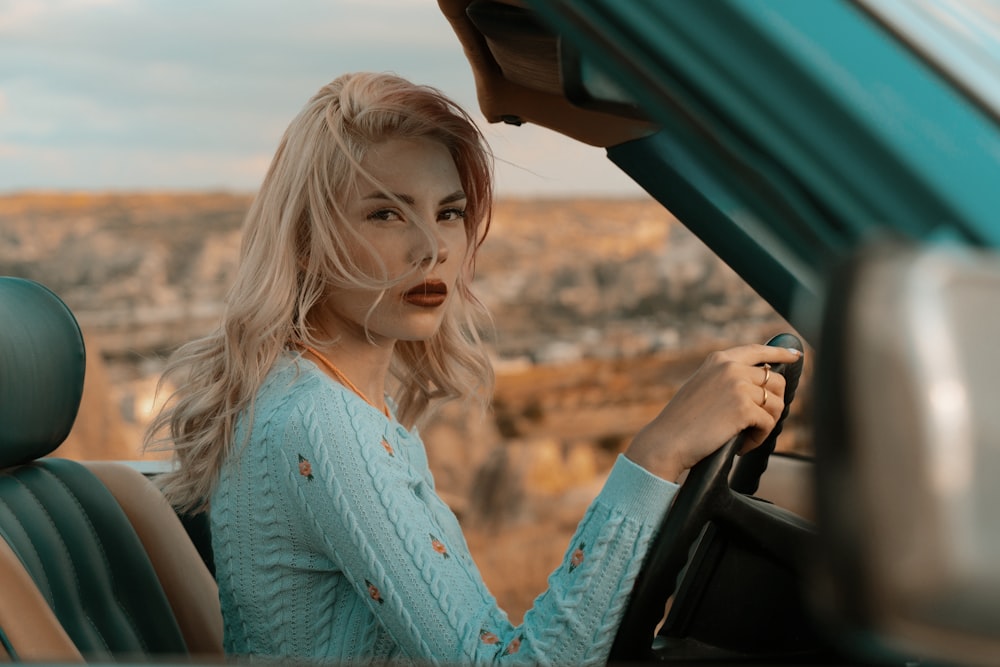 woman in blue button up long sleeve shirt holding car steering wheel during daytime