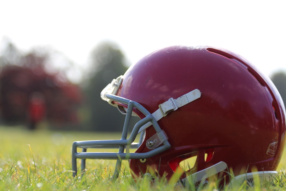 Casque de football rouge sur l’herbe verte pendant la journée