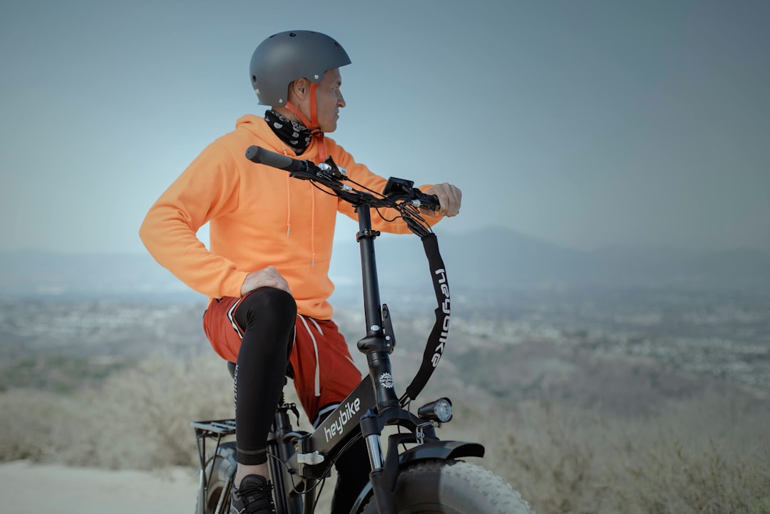 man in orange hoodie and red pants riding black mountain bike