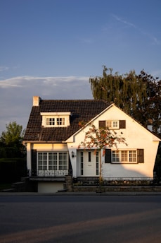 white and brown concrete house near green trees under blue sky during daytime