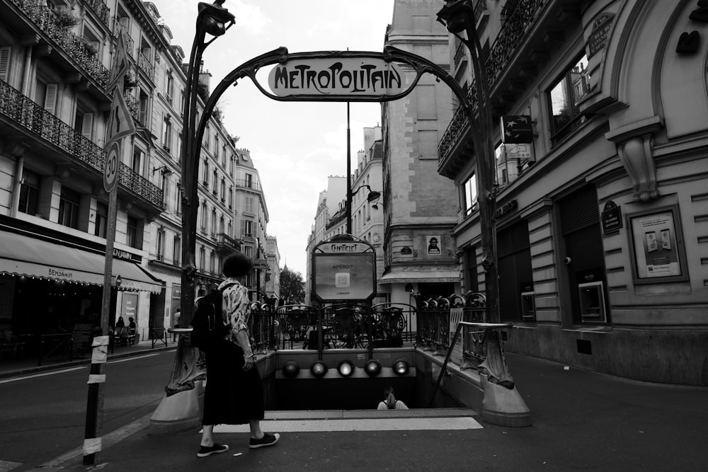 grayscale photo of people walking on street near buildings