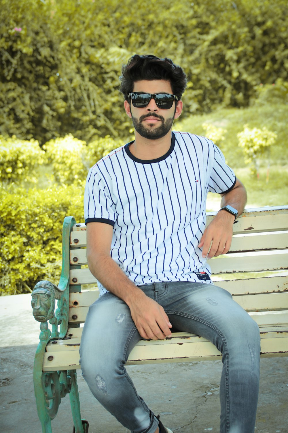 man in white and blue striped crew neck t-shirt sitting on brown wooden bench during