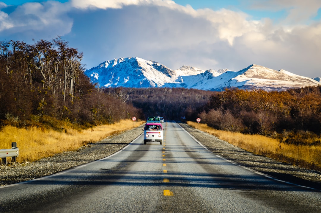red car on road near mountain range, vanlife travel road to ushuaia - argentina @Sentidos.humanos