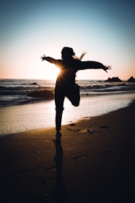 silhouette of woman standing on beach during sunset
