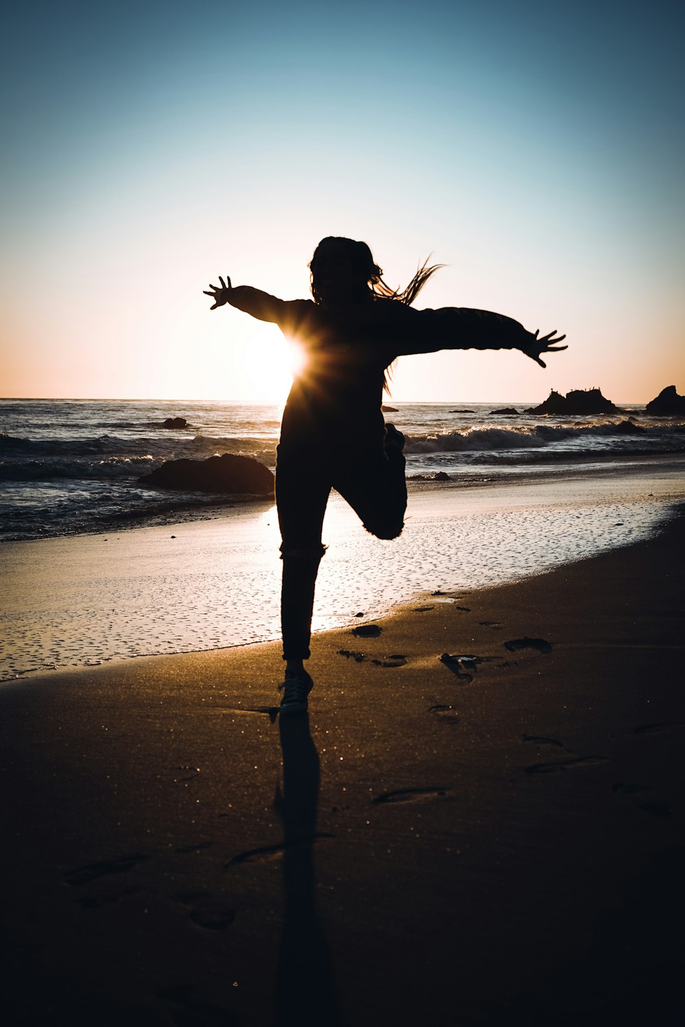 silhouette of woman standing on beach during sunset